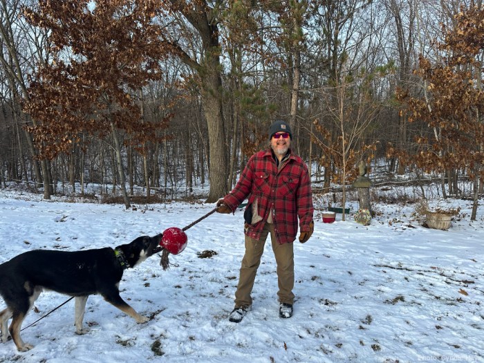 standing in tattered shirt playing with dog
